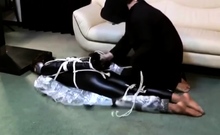 Asian girl mummified in black zentai while tied